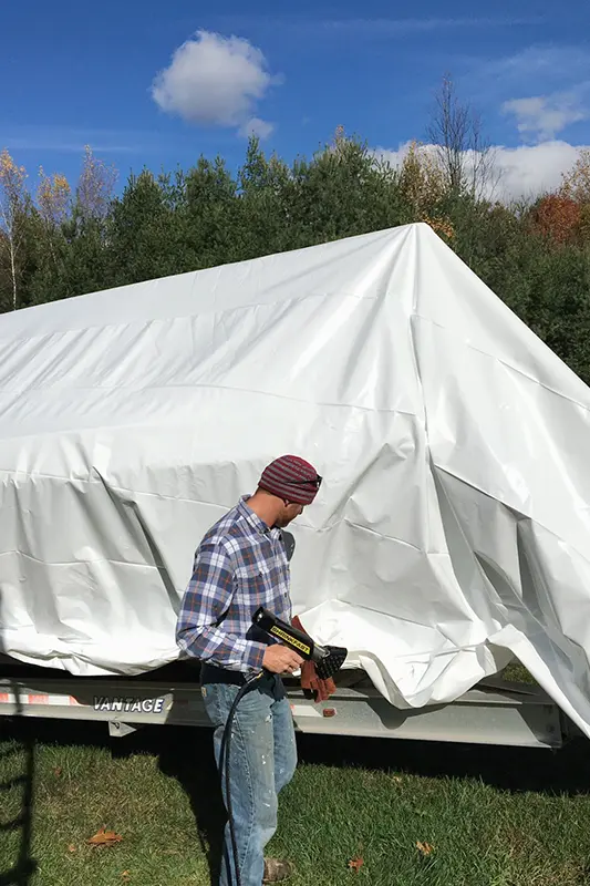 Marine technician shrink-wrapping a boat with vents and a zippered access door at South Hero—boat shrink wrap in Vermont