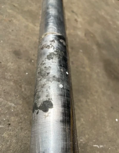 Close-up of corroded stainless steel shaft surface requiring marine welding repair.