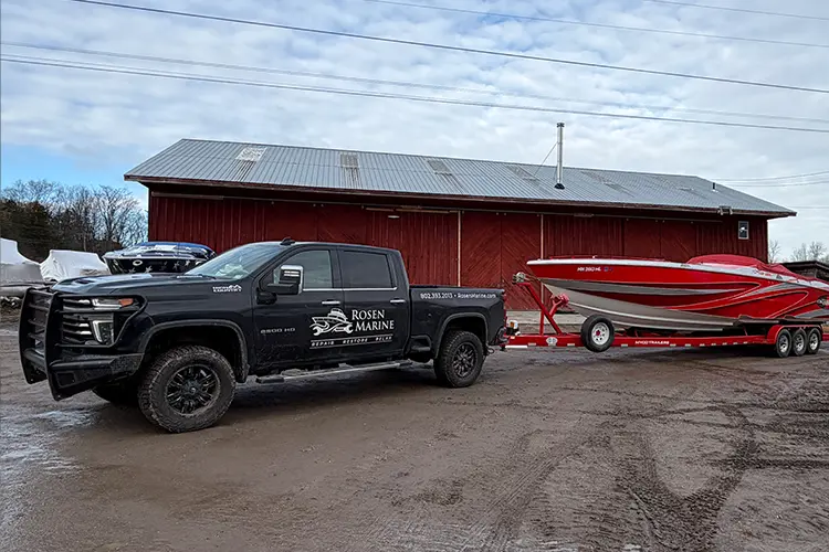 Winter boat hauling from Fort Myers and nationwide with Rosen Marine truck towing a red powerboat on a hydraulic trailer.
